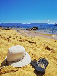 Beach by sea against clear blue sky