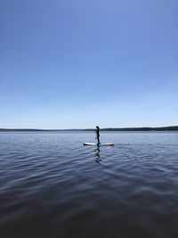 Young woman  surfing in sea against clear sky