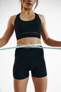 Midsection of young woman standing against white background