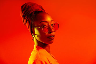 Portrait of young man wearing eyeglasses against red background