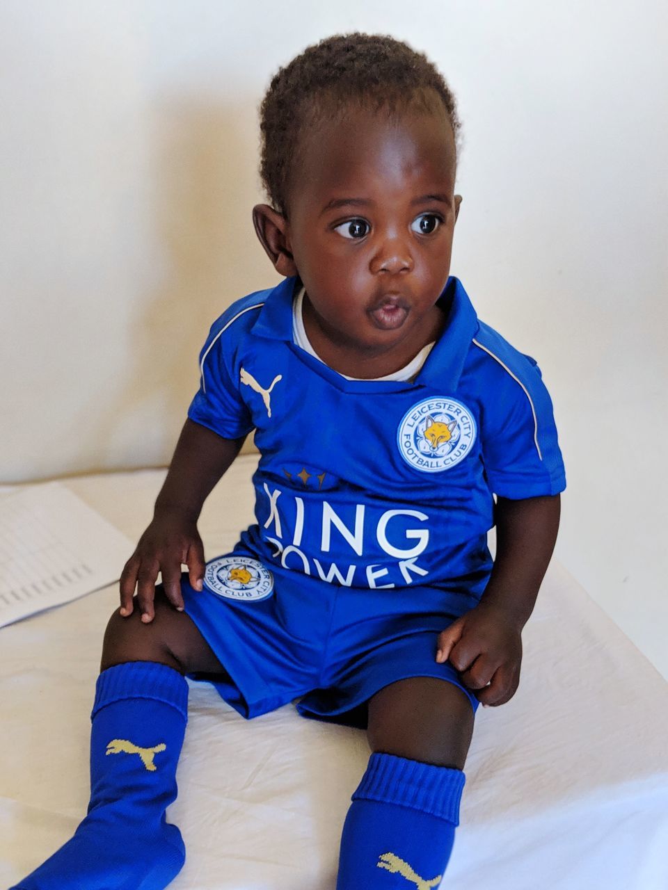 PORTRAIT OF CUTE BOY SITTING AGAINST BLUE BACKGROUND