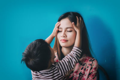 Portrait of mother and daughter against blue wall