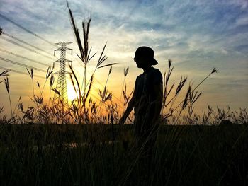 Silhouette man on landscape against sky during sunset