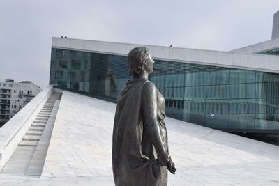 Rear view of statue against modern building in city