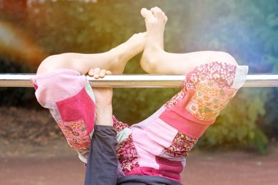 Low section of girl exercising on gymnastics bar