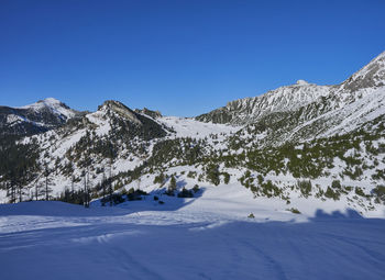 Scenic view of snowcapped mountains against clear blue sky