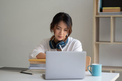 Mid adult woman using mobile phone while sitting on table