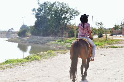 Rear view of young woman riding horse