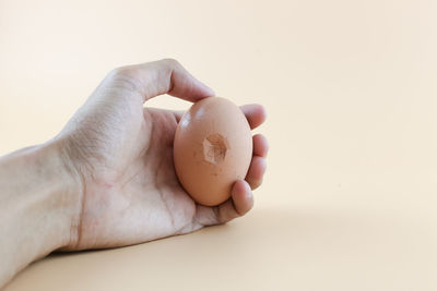 Close-up of hand holding ice cream over white background