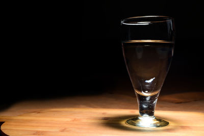 Close-up of beer glass on table against black background