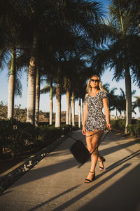 Full length portrait of young woman against trees