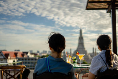 People sitting at restaurant against buildings in city