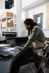 Side view of young businesswoman working on table