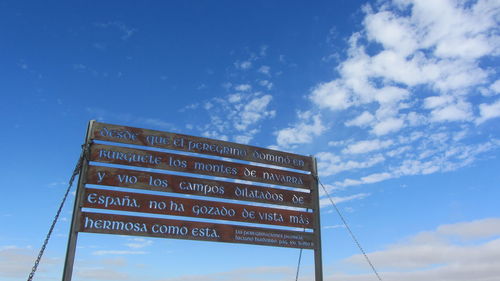 Low angle view of information sign against blue sky