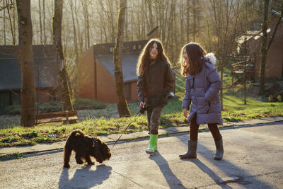 Girls walking with dog on footpath