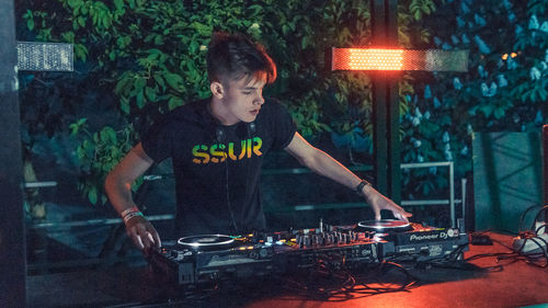 Man standing by illuminated lighting equipment at night