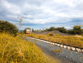 Railroad track amidst field against sky