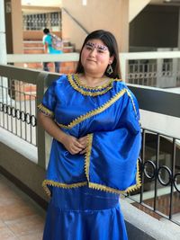 Portrait of woman wearing blue traditional clothing against railing