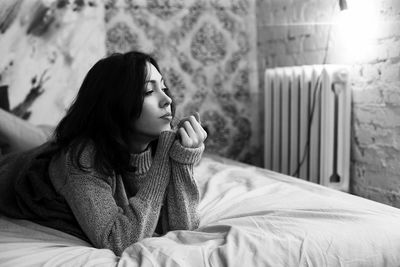 Young woman sitting on bed at home