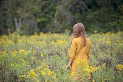 Young girl in yellow dress in a field of flowers