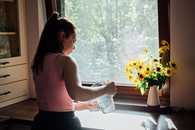 Young woman drinking water from glass in the kitchen. caucasian female model holding transparent