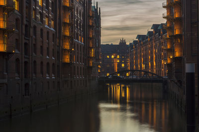 Canal amidst buildings in city at night