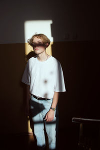 Portrait of young woman standing against wall