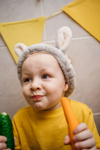 Baby in rabbit ears eats vegetables carrot cucumber easter