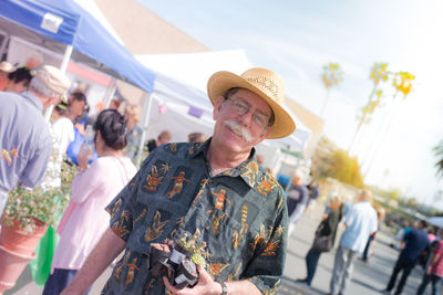 Portrait of happy man holding potted plants in market