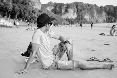 Full length of man sitting on sand at beach