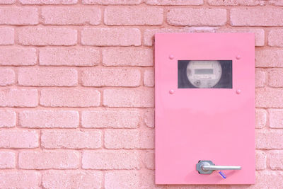 Close-up of telephone booth against brick wall