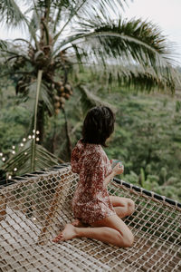 Rear view of woman standing against palm trees