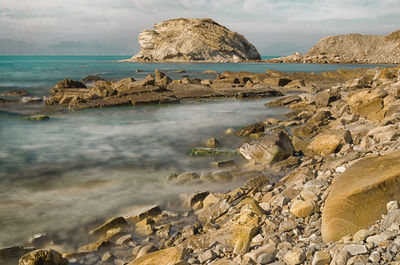 Scenic view of rocks in sea against sky