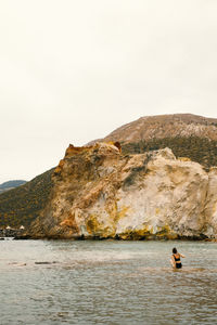 Man surfing on rock against sky