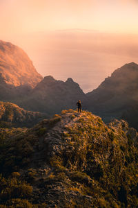 Man on mountain against sky during sunset