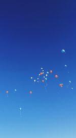 Low angle view of balloons against clear blue sky