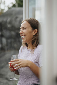 Happy woman laughing while holding wineglass during dinner party at cafe