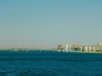 Scenic view of sea and buildings against clear sky