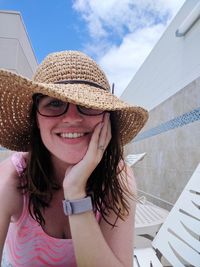 Portrait of smiling young woman wearing hat against sky