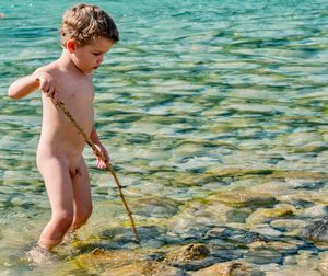 Full length of shirtless boy standing in sea