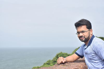 Young man looking at sea against sky