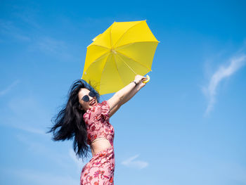 Low angle view of woman against blue sky