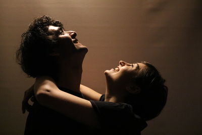 Profile view of couple looking up while embracing against wall