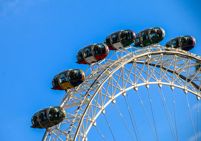 Low angle view of ferris wheel against clear blue sky