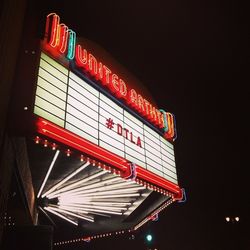 Low angle view of illuminated information sign at night