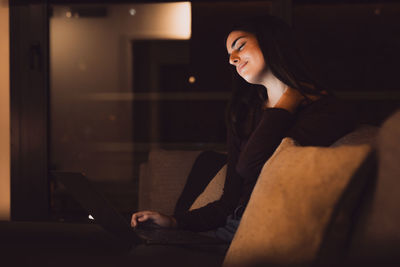 Young woman sitting on sofa at home