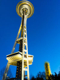 Low angle view of illuminated tower against clear blue sky