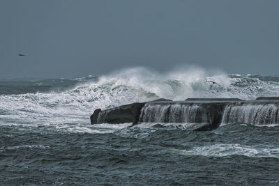Storm surge creates high waves crashing on a jetty.
