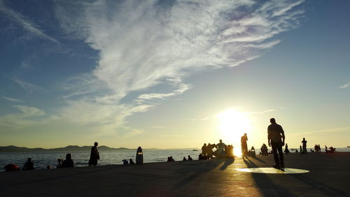 People on beach against sky during sunset