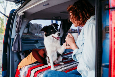 Woman holding dog paw while sitting in camper trailer